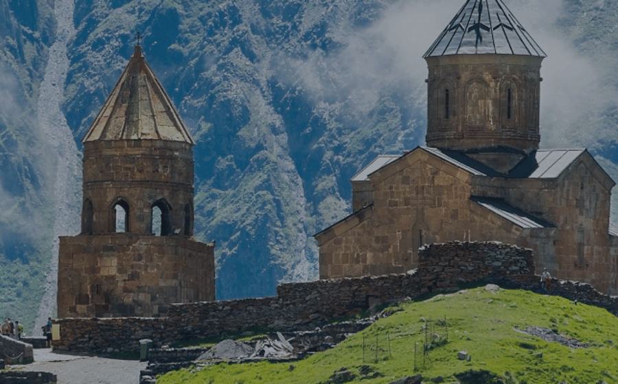 Old stone church above a green valley in the Caucasus mountains